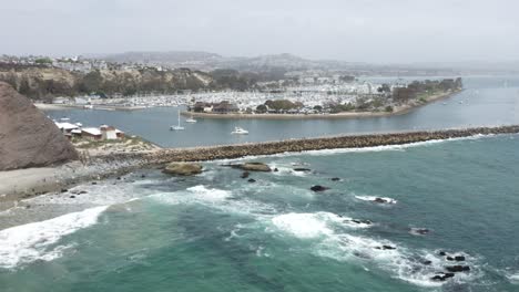 pushing-in-dolly-aerial-of-dana-point-California-with-its-yachts-boats-paddle-boarders-clean-beaches-elegant-homes-sea-walls-and-turquoise-water-from-the-air-and-bird's-eye-perspective