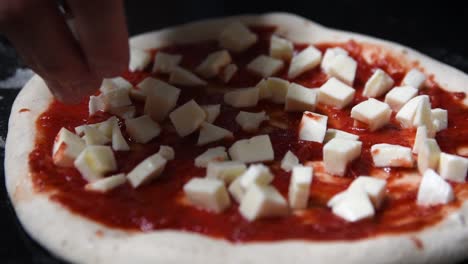 Close-up-shot-of-chef-making-home-made-sourdough-pizza-with-salsa-and-mozzarella-cheese-cubes