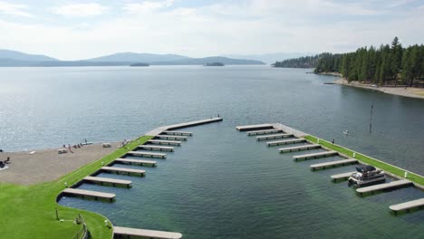 Aerial-of-a-boat-dock-marina-over-lake-with-mountains-in-background