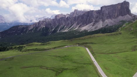 Aerial-of-car-drive-on-mountain-range-road-in-green-landscape,-Passo-Giau