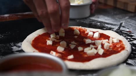 Chef-putting-mozzarella-cheese-on-home-made-sourdough-pizza-with-salsa