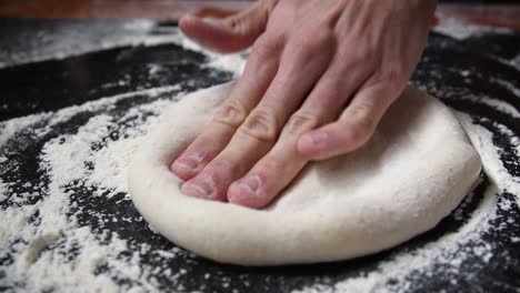 Close-up-shot-of-chef-stretching-sourdough-with-hands-for-home-made-pizza