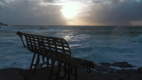 Rusty-metal-bench-overlooking-a-stormy-sea-with-a-dark-cloudy-sky