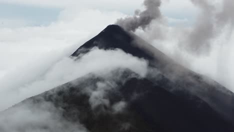 Drone-video-of-an-active-volcano-half-covered-by-clouds-in-Antigua,-Guatemala