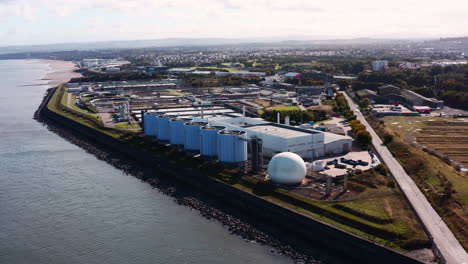 Aerial-shot-approaching-a-sewage-plant-by-the-sea-on-the-outskirts-of-Edinburgh-on-a-sunny-day