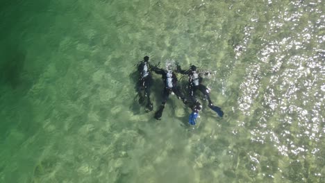 Three-scuba-divers-dive-at-shore-in-alpine-lake-with-turquoise-water