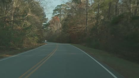Driving-down-a-curving-two-lane-road-through-the-autumn-trees