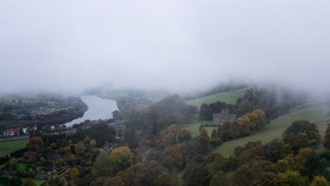 Herrenhaus-Liegt-Oberhalb-Eines-Flusses-In-Einem-Nebelverhangenen-Tal,-Umgeben-Von-Grünen-Bäumen-Im-Schottischen-Hochland