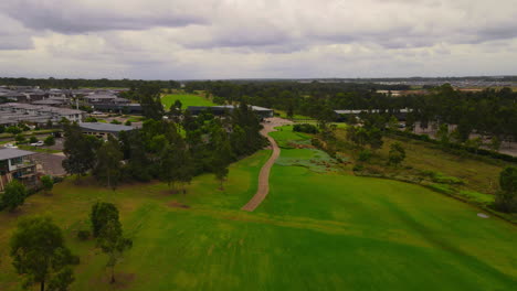 Fast-Drone-shot-of-Golf-Course-club-house-from-hole-cloudy-sky