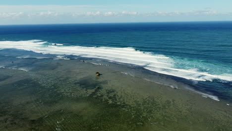 Waves-breaking-on-the-coral-reef-off-coast-of-Bolinao-beach-in-Philippines---aerial-drone-view