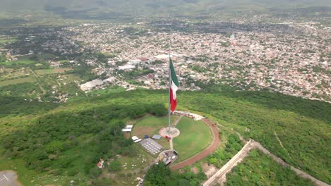 Flying-around-Mexican-Independence-flag-over-the-mountains-of-Iguala-in-Guerrero,-Mexico