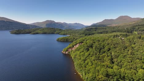Flying-Along-the-Side-of-Loch-Lomond-Shore-to-lift-up-and-Reveal-Ben-Lomond-and-Mountains