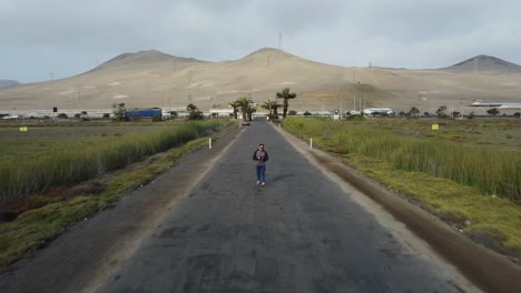 Person-walks-down-paved-road-in-between-grasslands