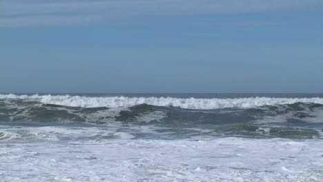 Medium-waves-crashing-against-shoreline-and-beach-in-Portugal