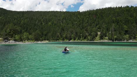 Two-young-men-are-rowing-a-boat-on-alpine-lake-with-turquoise-water