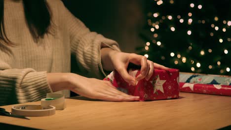 Woman-is-wrapping-a-Christmas-present-for-under-the-tree,-holiday-atmosphere-concept