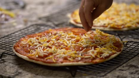 Nahaufnahme-Der-Hand,-Die-Geriebene-Käsezutat-Auf-Hausgemachte-Ungekochte-Pizza-Aufträgt