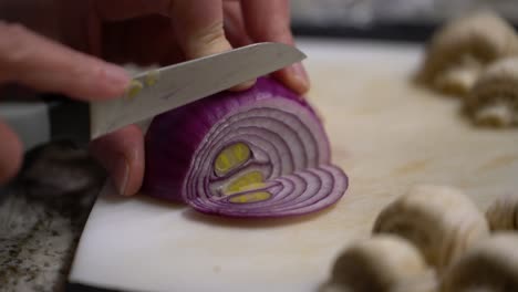 Handheld-close-up-of-hands-cutting-onion-with-paring-knife-in-home-kitchen