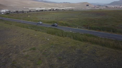 Cars-driving-through-paved-road-in-the-middle-of-grasslands
