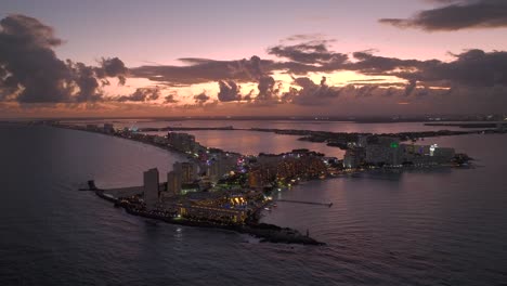 Aerial-view-in-front-of-the-Punta-Cancun-bay,-cloudy-sunset-in-Quintana-roo,-Mexico---ascending,-drone-shot