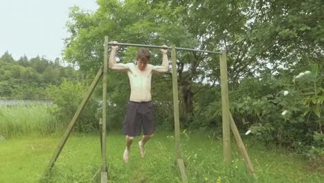 Young-fit-man-doing-behind-neck-pullups-outdoors-in-nature-Slow-Motion