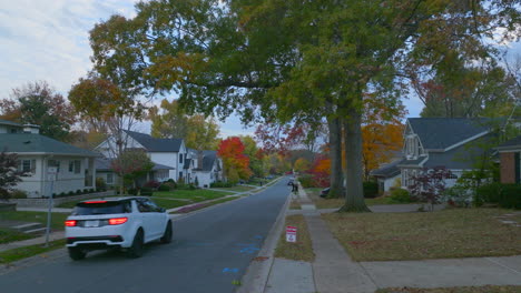 A-car-going-down-the-street-in-a-nice-neighborhood-pulls-into-a-driveway-as-camera-follows