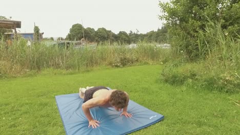 Young-athletic-man-doing-pushups-at-outdoor-home-gym