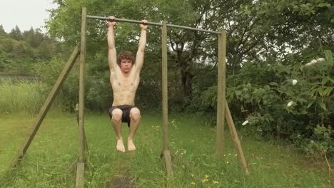 Fit-young-man-performs-hanging-tucked-need-raise-isometric-hold