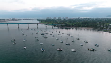 Cinematic-aerial-view-of-Coronado-marina-with-small-boats-anchored-near-the-bridge
