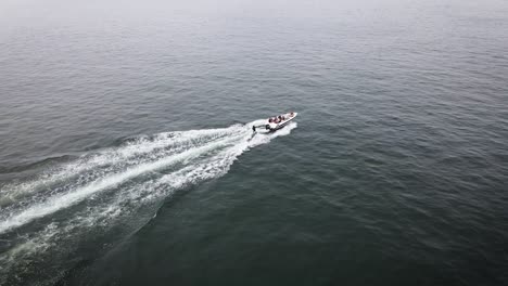 Drohnenaufnahme-Von-Freunden-In-Einem-Boot-Wakeboarden-Auf-Dem-Ozean-Im-Sommer-In-Lima-Peru