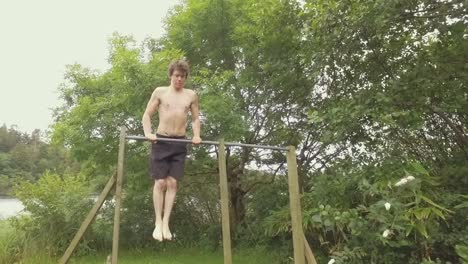 Young-man-exercises-by-doing-muscle-up-pullups-outdoors-on-home-gym