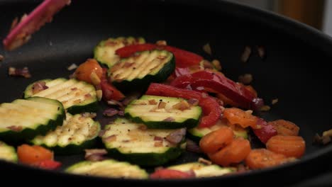 Static-slow-motion-shot-of-cooking-delicious-vegetables-with-zuchini,-peppers,-onions,-garlic-and-carrots-in-hot-pan-in-kitchen