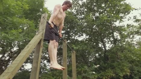 A-young-fit-shirtless-man-performs-muscle-up-exercise-outdoors-on-home-gym