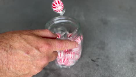 A-man-reaches-into-a-candy-jar,-takes-lots-of-lollies,-then-pulls-them-away
