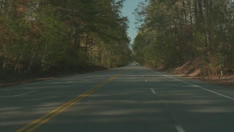 Conduciendo-Por-Una-Carretera-Bordeada-De-árboles-En-Otoño-Con-Hojas-De-Otoño-Por-Todas-Partes