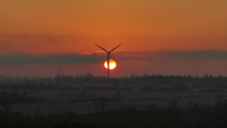 Aerial-close-up-of-a-turning-windmill-with-sun-in-behind-during-sunrise