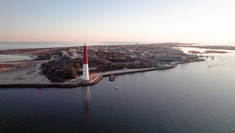 Aerial-drone-view-of-Barnegat-Lighthouse-and-view-down-Long-Beach-Island,-moving-overhead