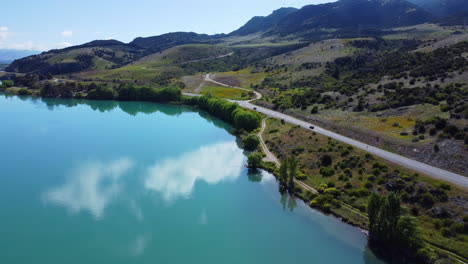 Drone-around-road-that-runs-along-blue-new-zealand-lake