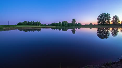 Peaceful-sunrise-with-the-colors-of-the-sky-reflecting-off-the-glassy-surface-of-a-lake---time-lapse
