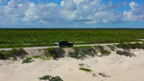 SUV-parking-near-empty-beach-in-Cozumel-Mexico-on-sunny-day,-aerial