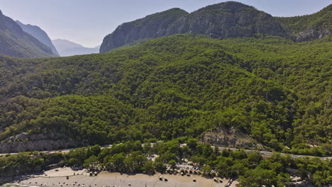 Antalya-Turkey-Aerial-v50-flyover-topman-beach-with-people-swimming-in-the-sea,-tilt-up-reveal-tünek-tepe-mountain-ranges,-coastal-woodland-with-dense-vegetations---Shot-with-Mavic-3-Cine---July-2022