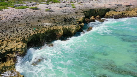aerial-of-tropical-waves-violently-crashing-onto-sharp-rocks-on-sunny-day-in-Cozumel-Mexico