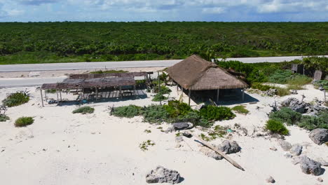 abandoned-hut-on-white-sand-beach-in-Cozumel-Mexico-near-coastline-jungle,-aerial
