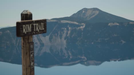 Trailhead-sign-rack-focus-to-lake-and-mountains-in-the-background