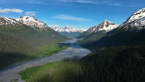 Lecho-De-Secado-Que-Atraviesa-Un-Exuberante-Valle-Entre-Montañas-Parcialmente-Cubiertas-De-Nieve-En-Alaska,-Ee.uu.
