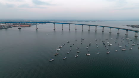 Aerial-overview-of-San-Diego-Bay-with-Coronado-Bridge-and-marina-with-small-boats-on-the-surface-of-dark-blue-Pacific-Ocean