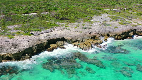 overhead-aerial-of-turquoise-blue-waves-crashing-onto-sharp-rocks-on-Cozumel-Island-in-Mexico