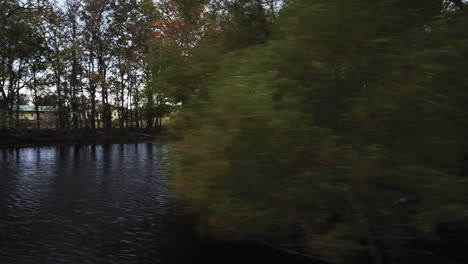 Aerial-drone-pan-shot-flying-over-a-lake-surrounded-by-trees-on-a-windy-day
