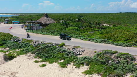 tourists-driving-scooter-on-empty-coastline-road-in-Cozumel-Mexico,-aerial