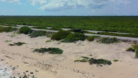 SUV-driving-on-empty-coastline-road-along-sandy-beach-of-Cozumel-Mexico